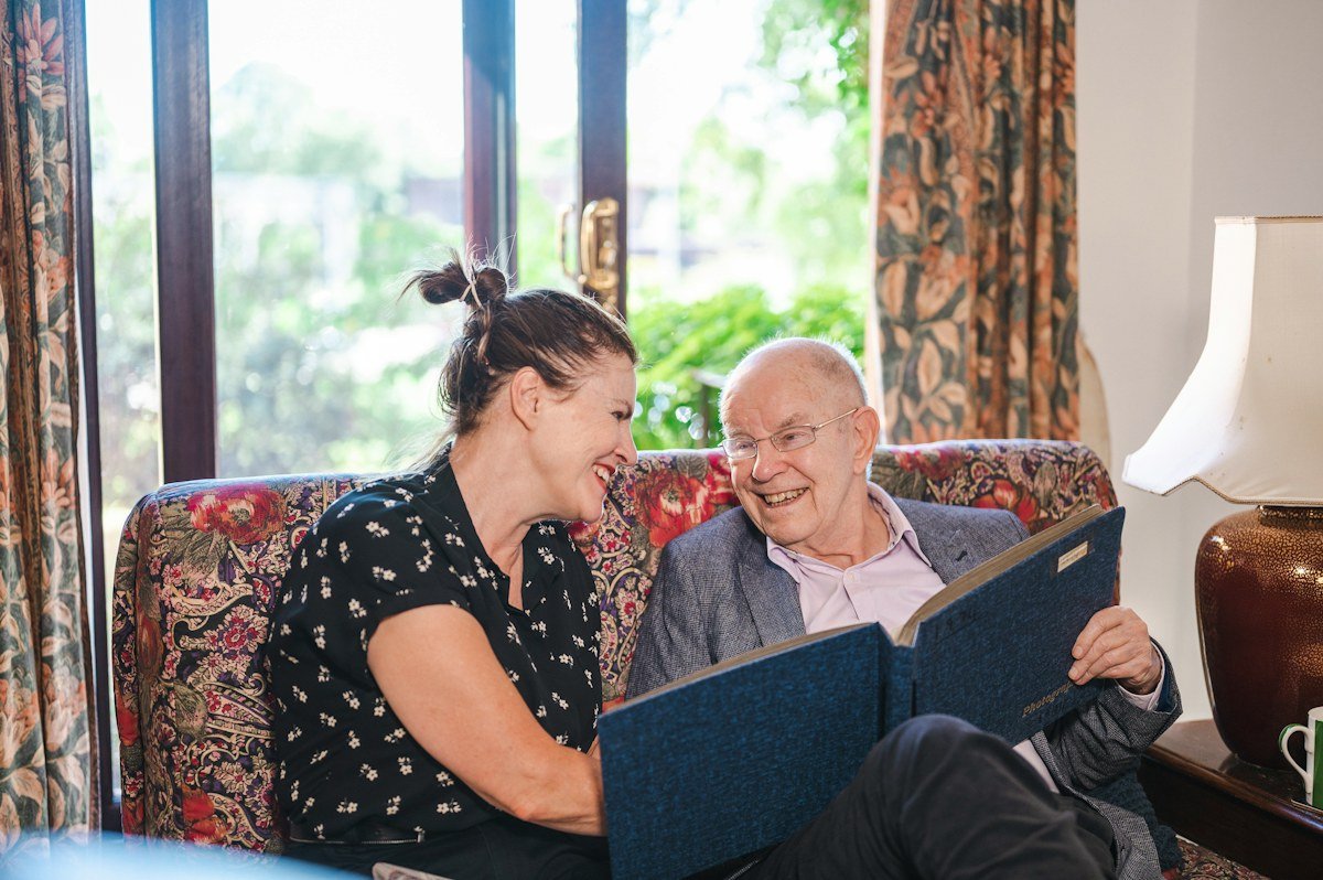 Older man reading with a supportive family member at home