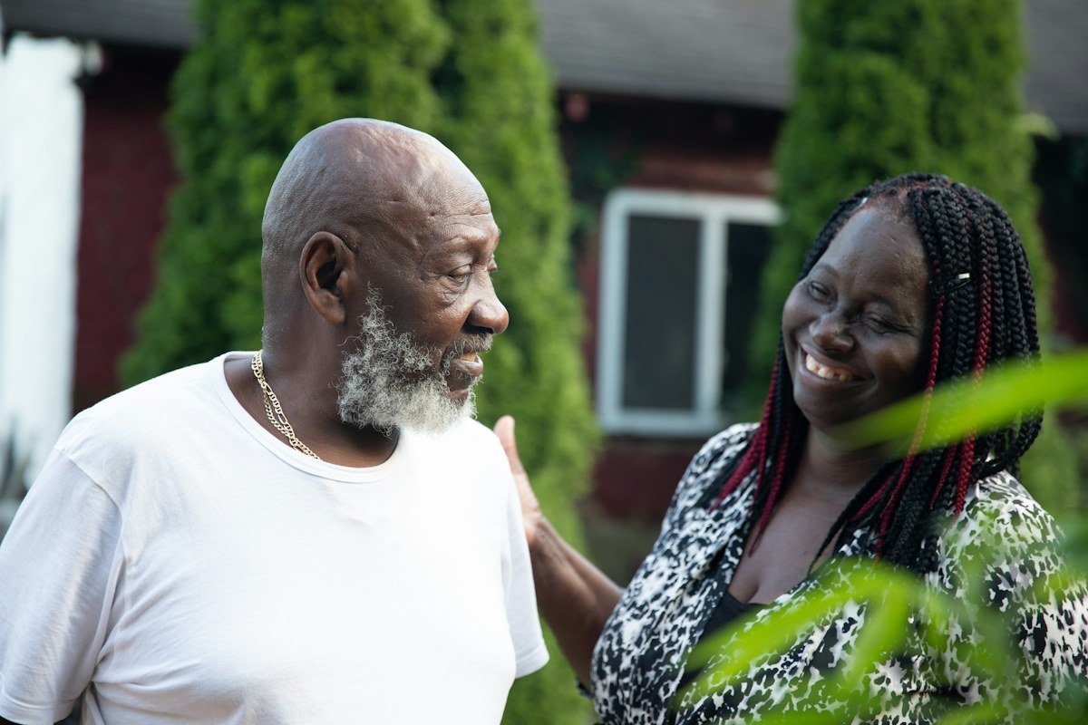 Older man and adult daughter smiling together while discussing senior care options
