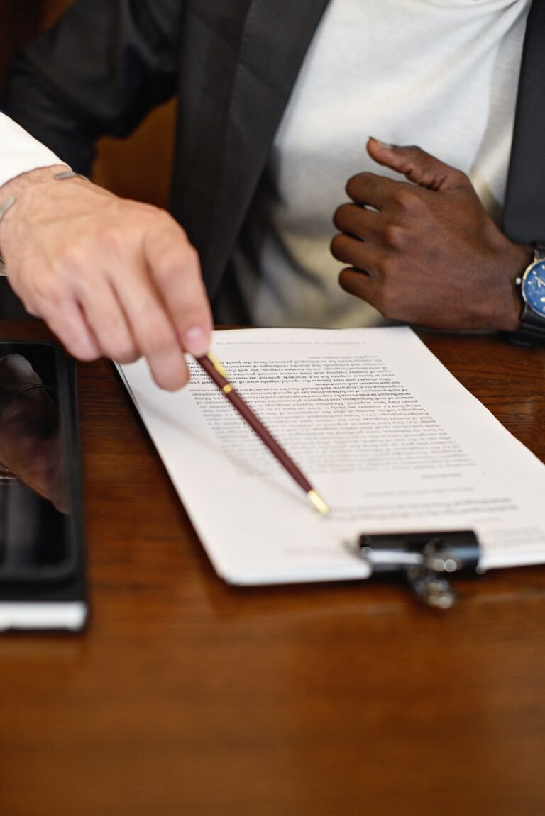 Two people reviewing a document on a clipboard, with one pointing to it using a pen.
