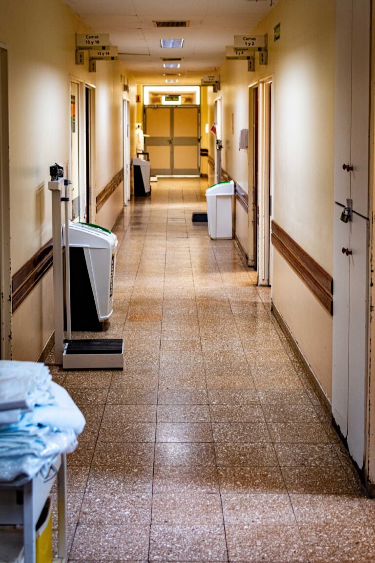 Quiet empty healthcare corridor with medical equipment along the hallway.