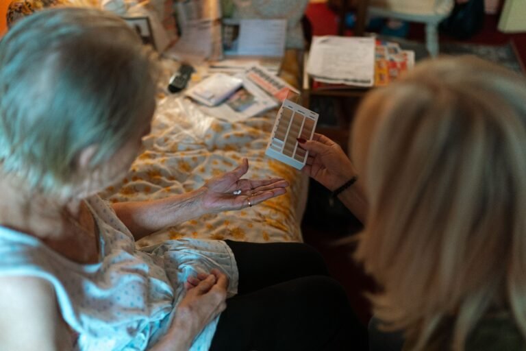 Caregiver assisting an older woman with medication at home