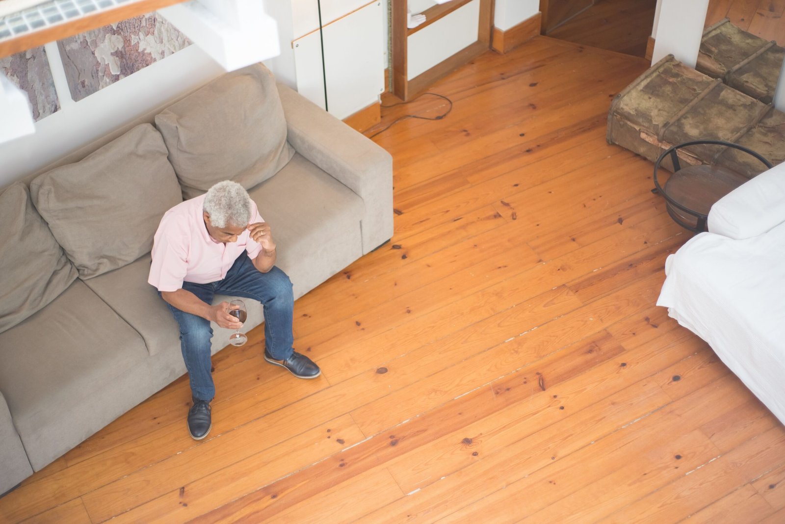Older man drinking an alcoholic beverage at home.