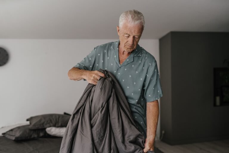 Older adult making a bed in a home setting.