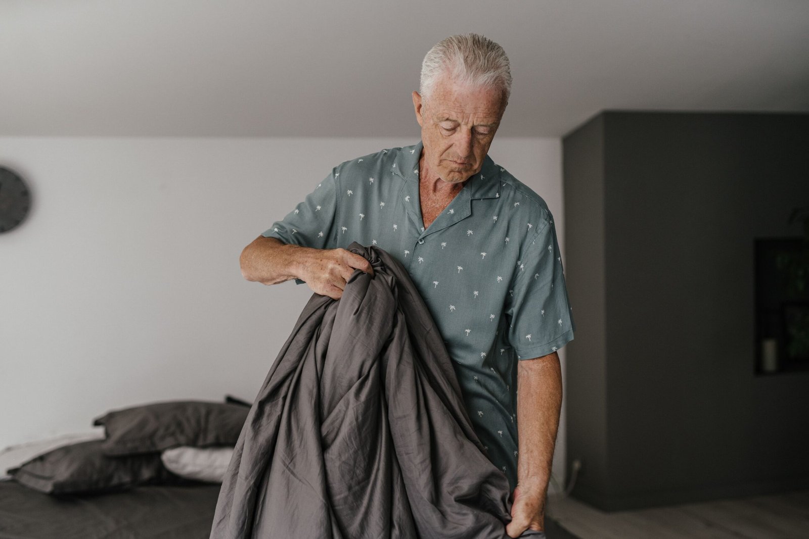 Older adult making a bed in a home setting.