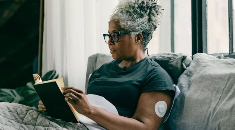 Older woman wearing a continuous glucose monitor while reading at home