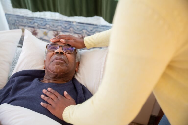 Caregiver attending to an older adult resting in bed.