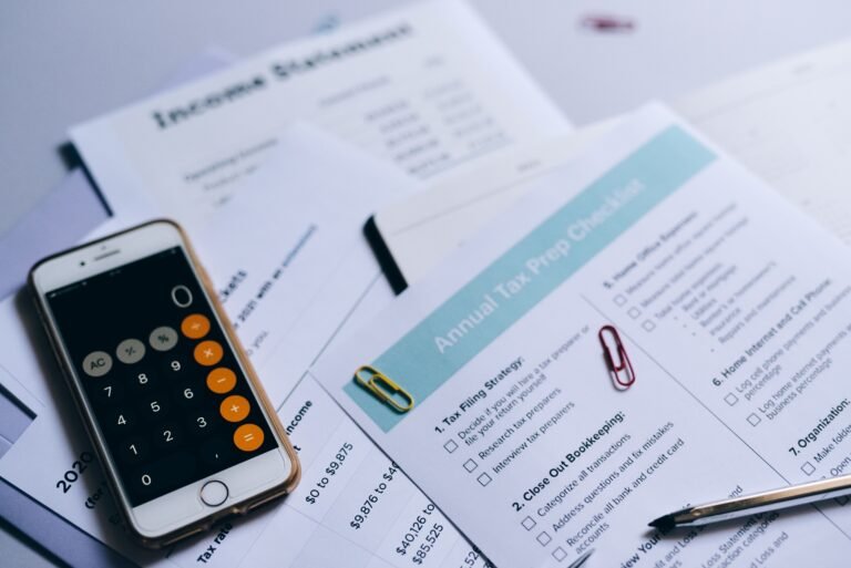 Smartphone, calculator, and accounting documents arranged on a desk.