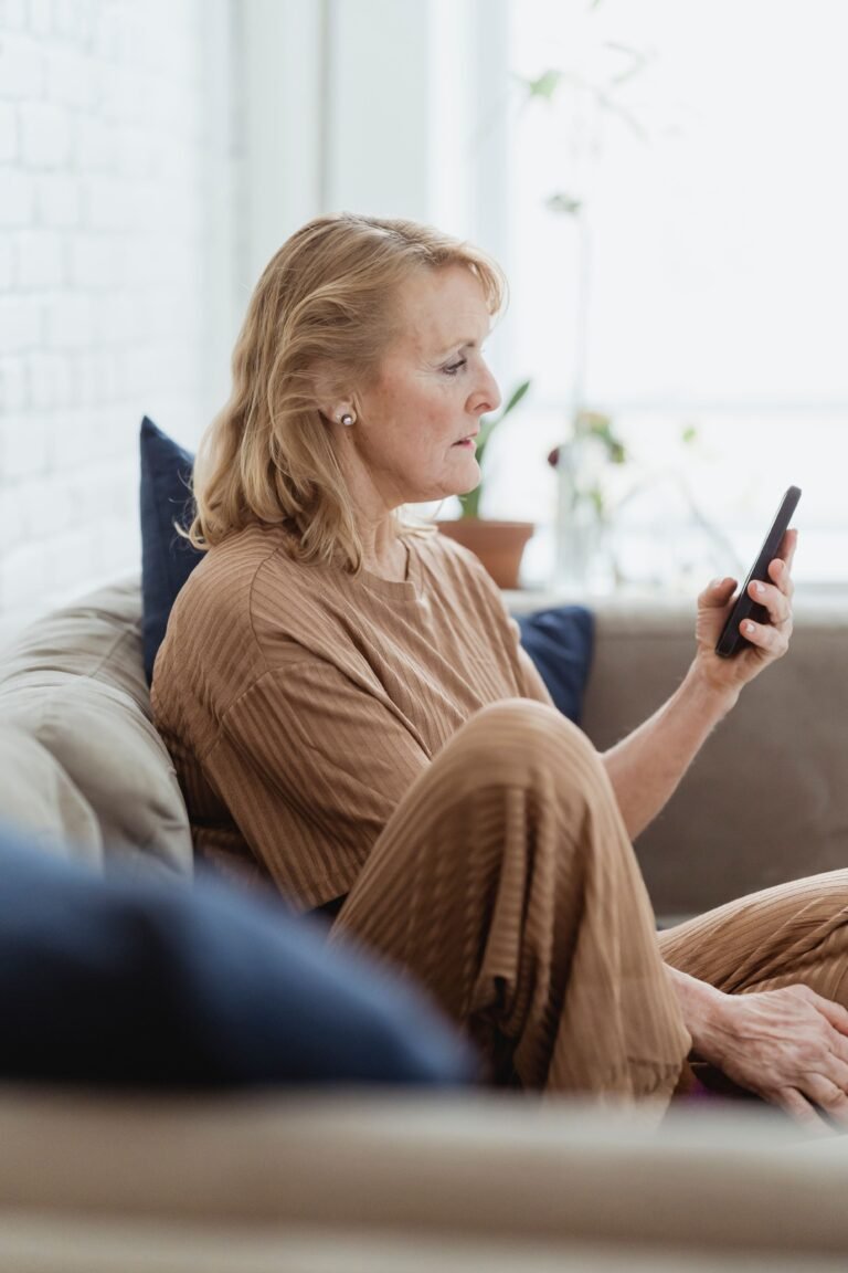 Older adult using a smartphone while sitting at home.