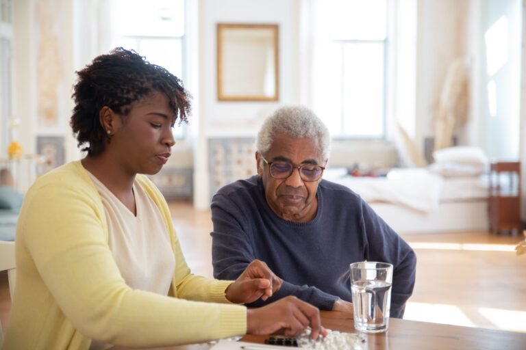 Caregiver explaining medication to an older man at home
