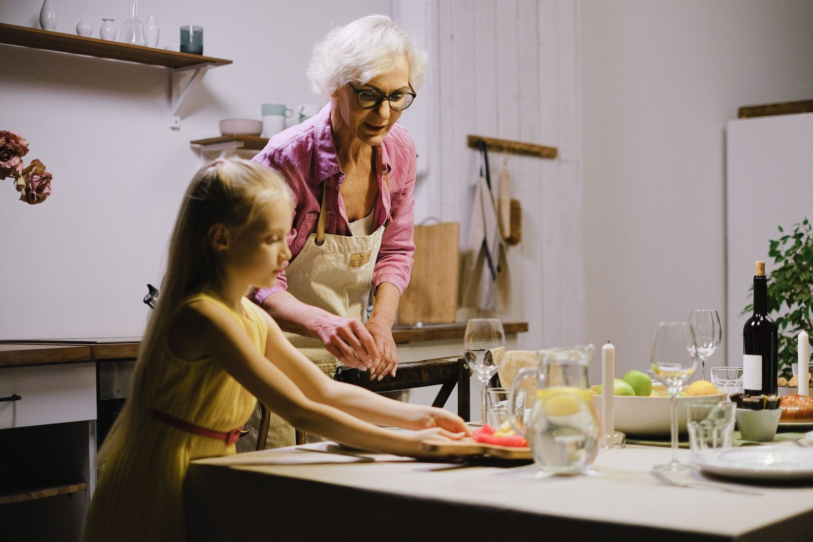 Older woman and family member setting a dining table together.