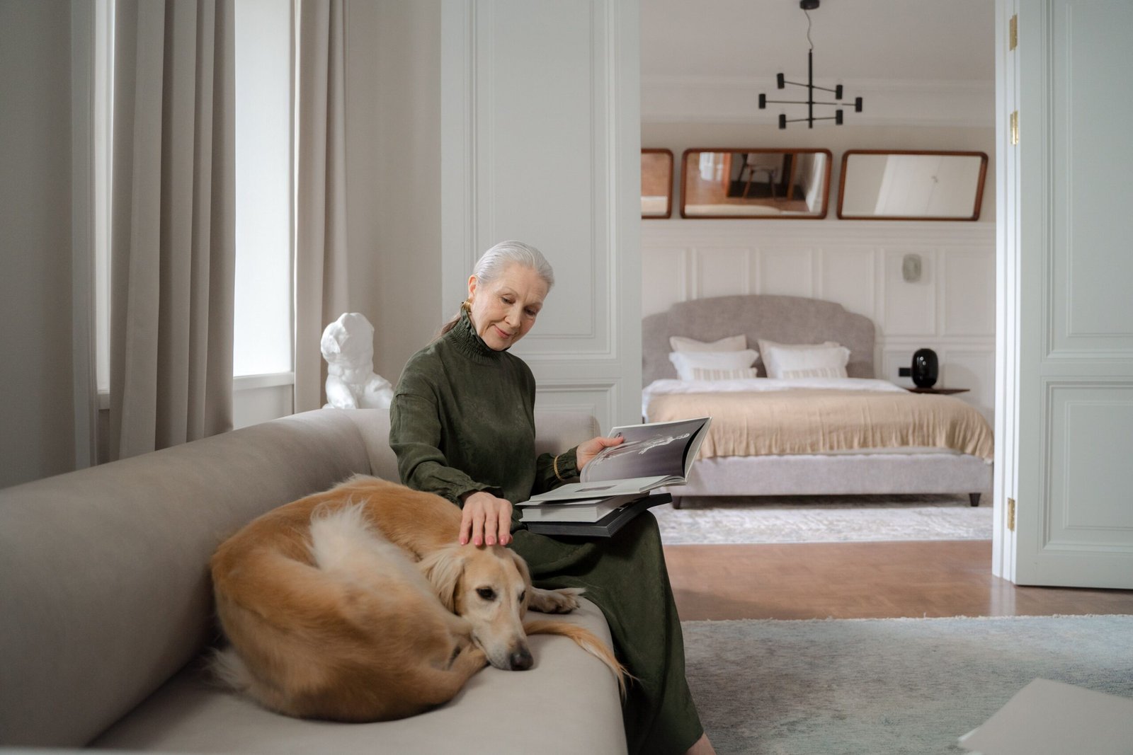 Older woman reading on a sofa while petting her dog