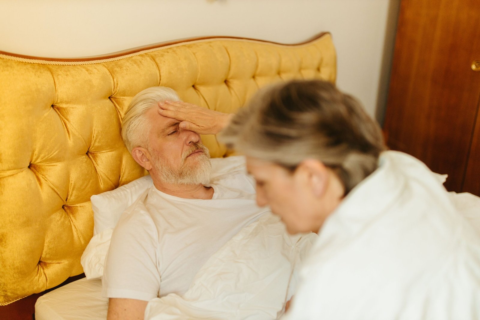 Caregiver checking on an older adult resting in bed.