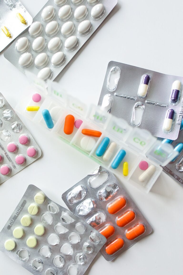 Assorted pills and blister packs beside a medication organizer