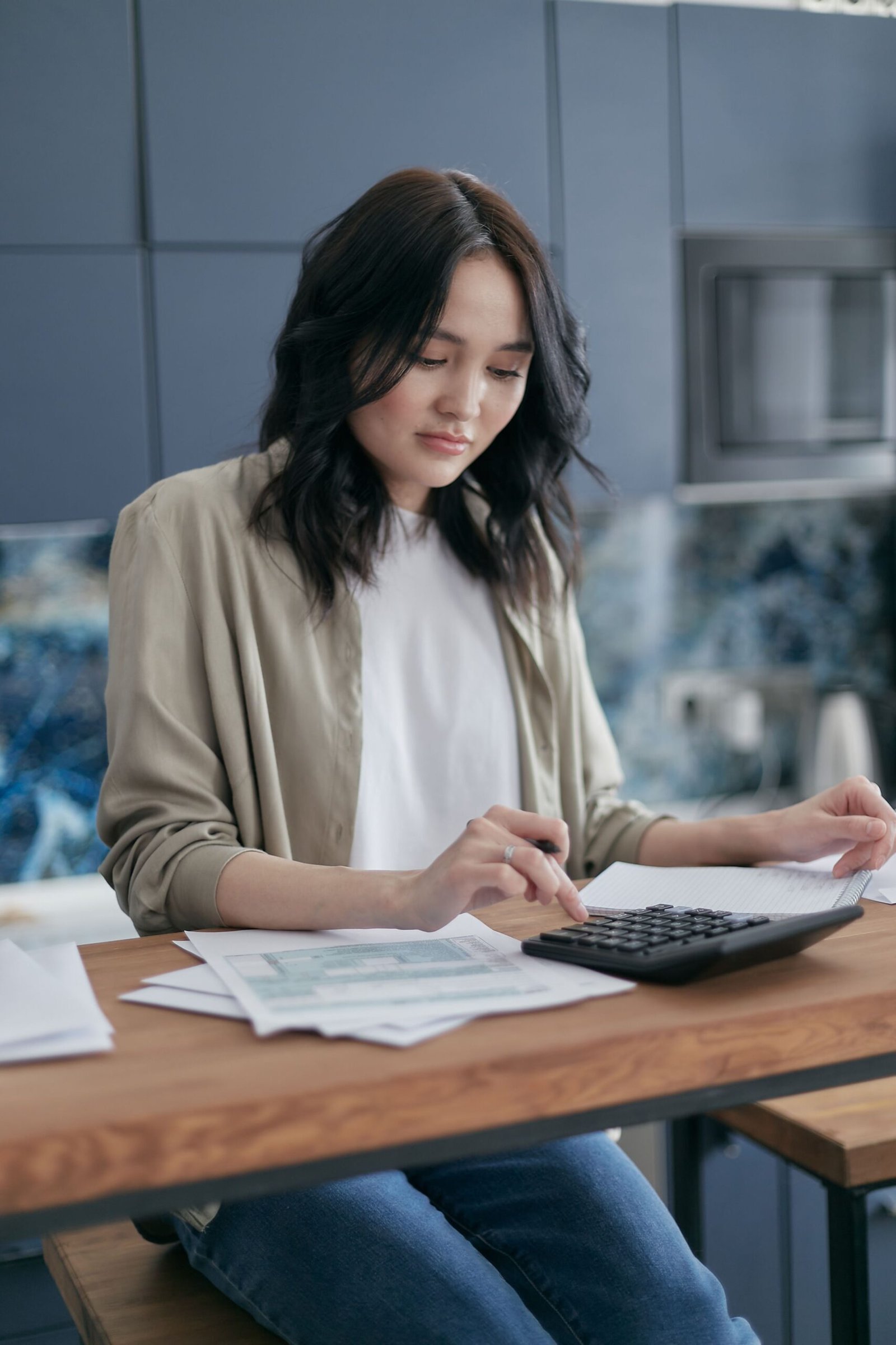 Person reviewing household bills with a calculator at a desk.
