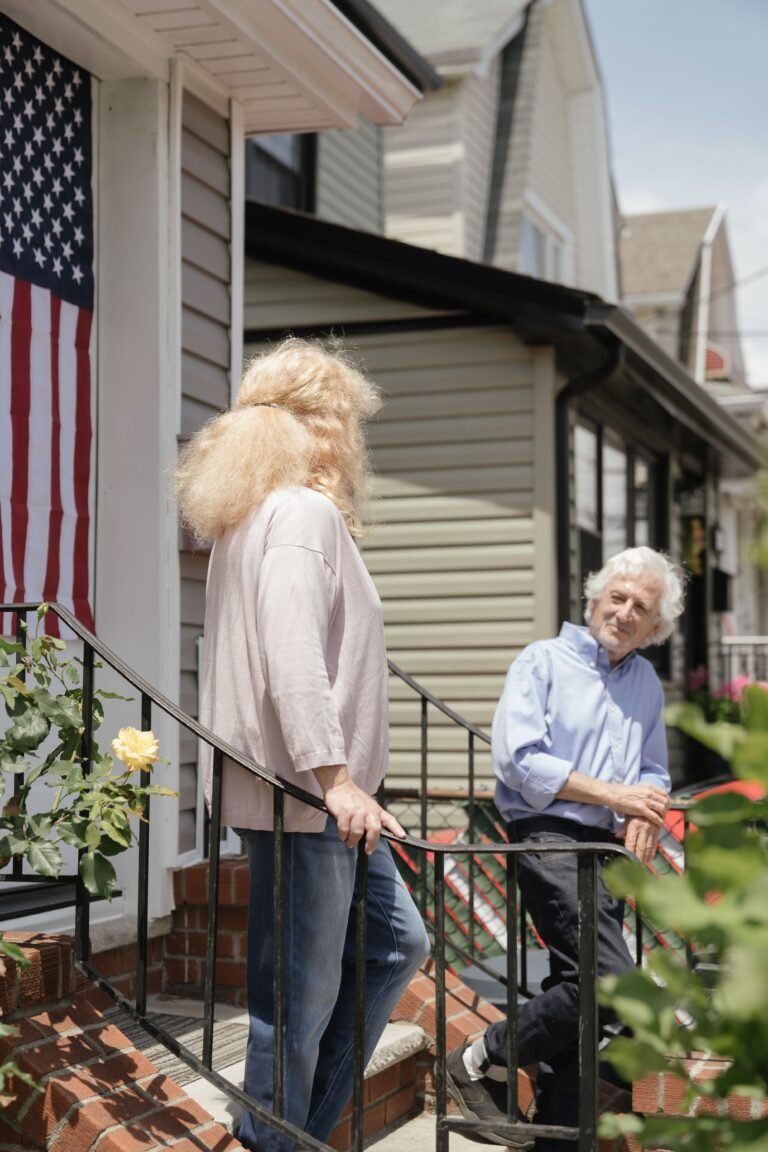 Older couple talking outside a home on a porch.