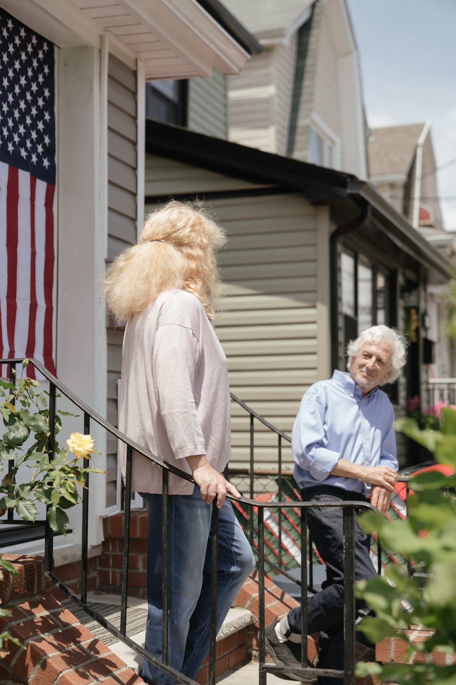 Older couple talking outside a home on a porch.