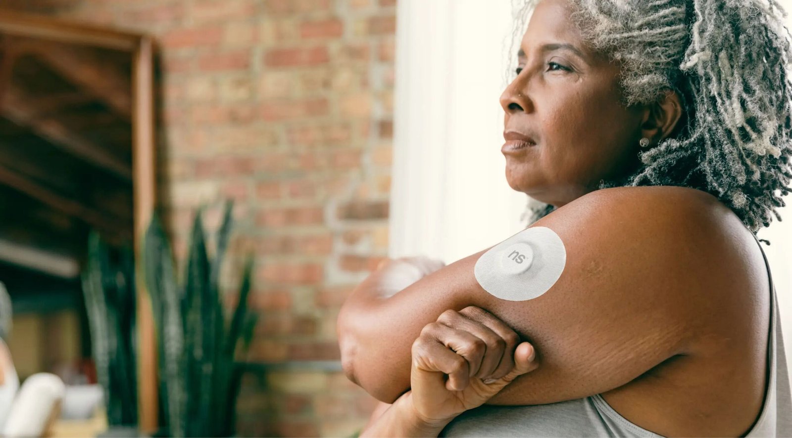 Older adult wearing a glucose monitoring sensor on the upper arm