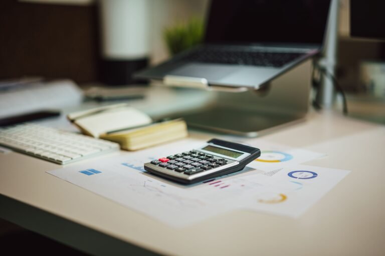 Laptop, calculator, and documents arranged on a modern desk.