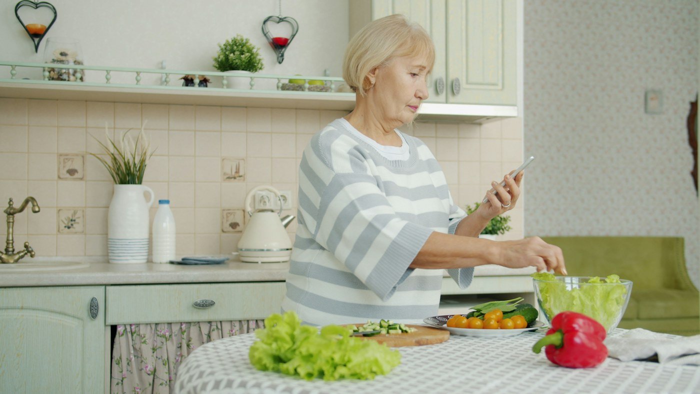 Older woman preparing a vegetable salad in her home kitchen