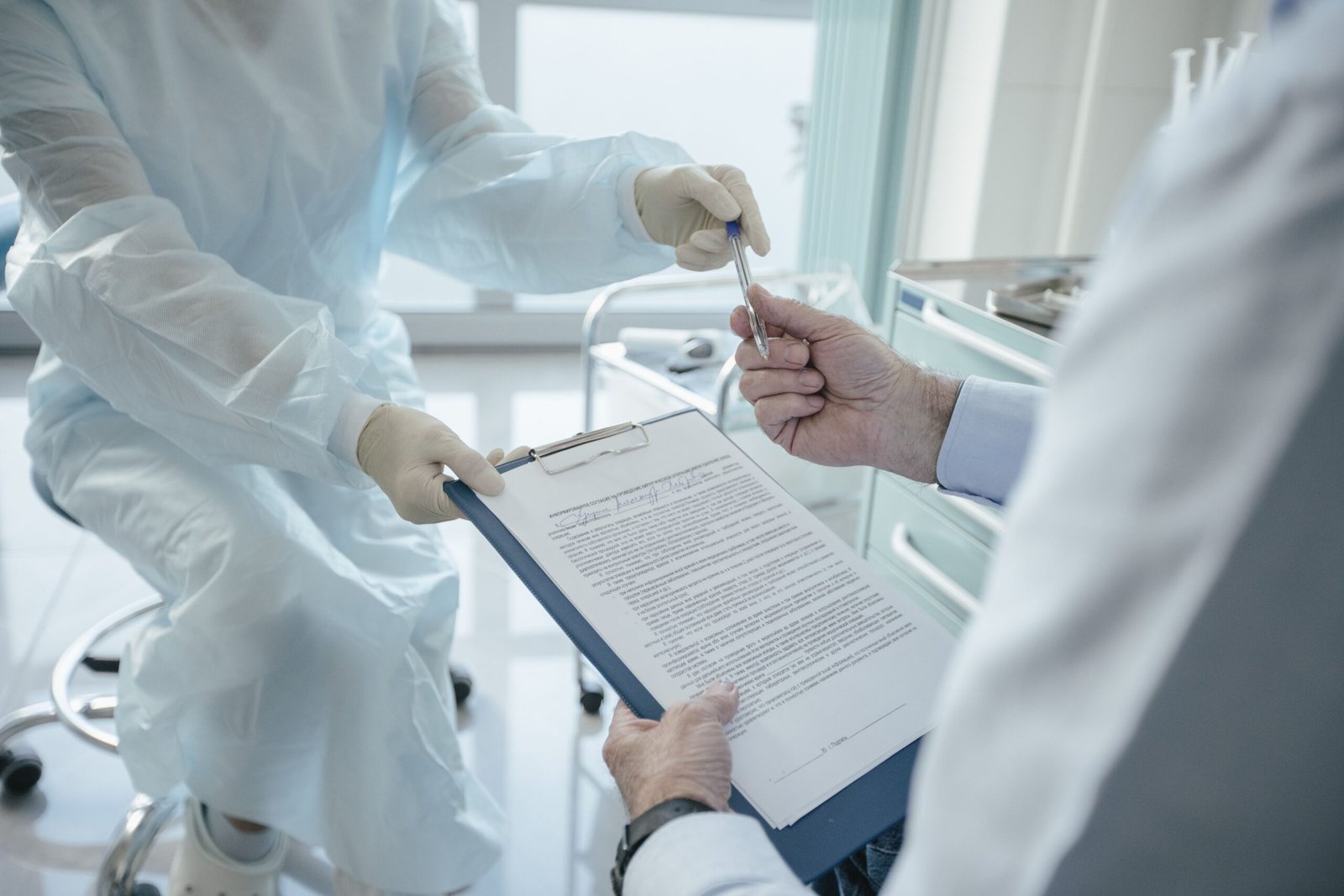 Healthcare professional handing a clipboard document to another person.