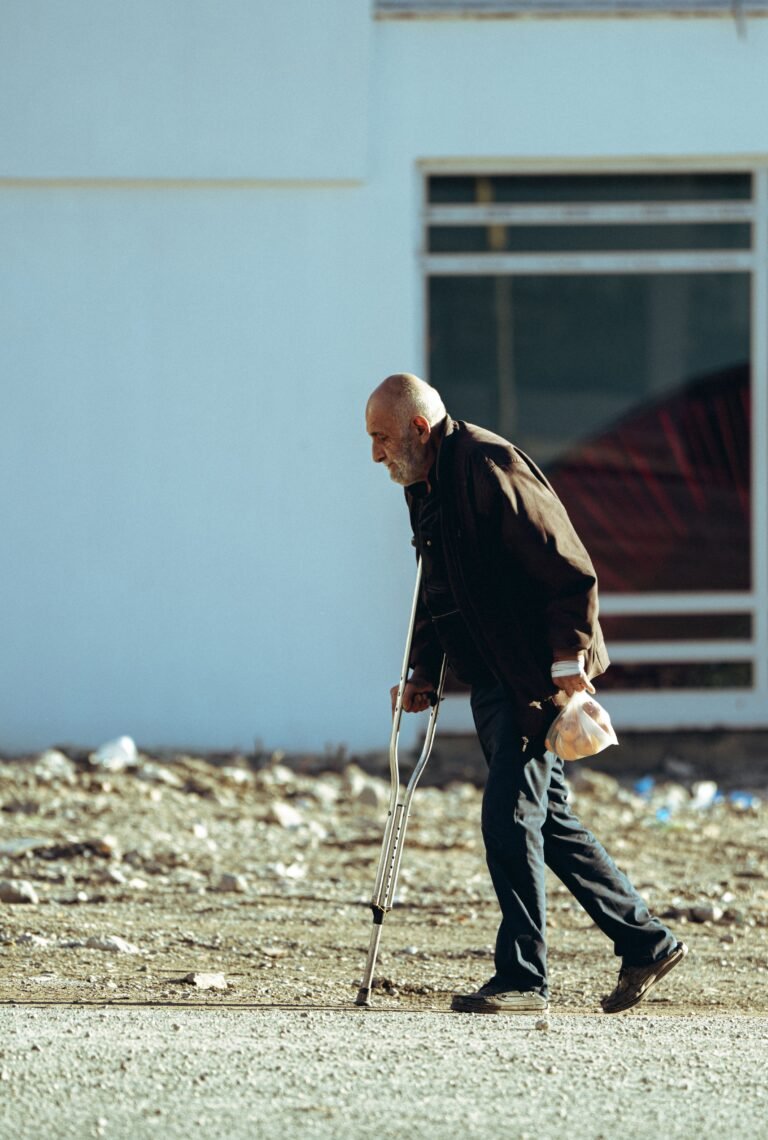 Older adult using crutches while walking outdoors.