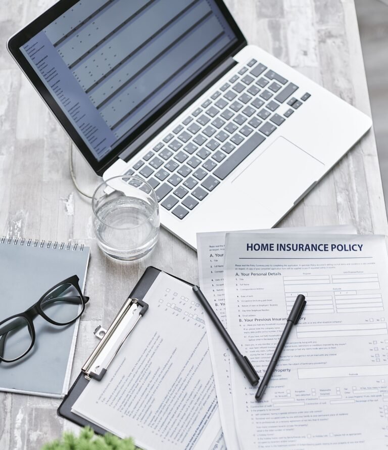 Insurance and financial planning documents arranged beside a laptop.