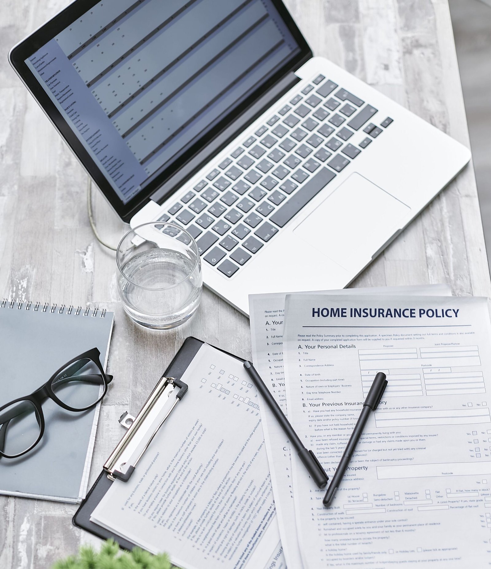 Insurance and financial planning documents arranged beside a laptop.