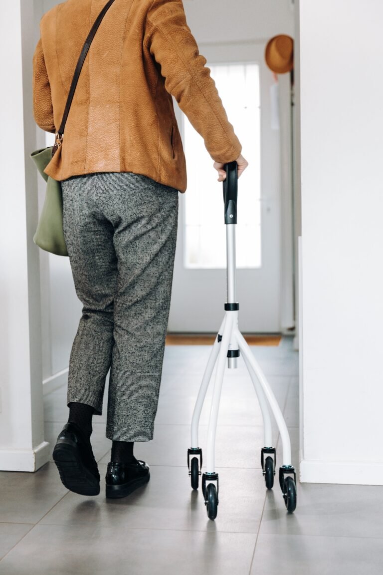 Older adult using a rolling walker in a home hallway.