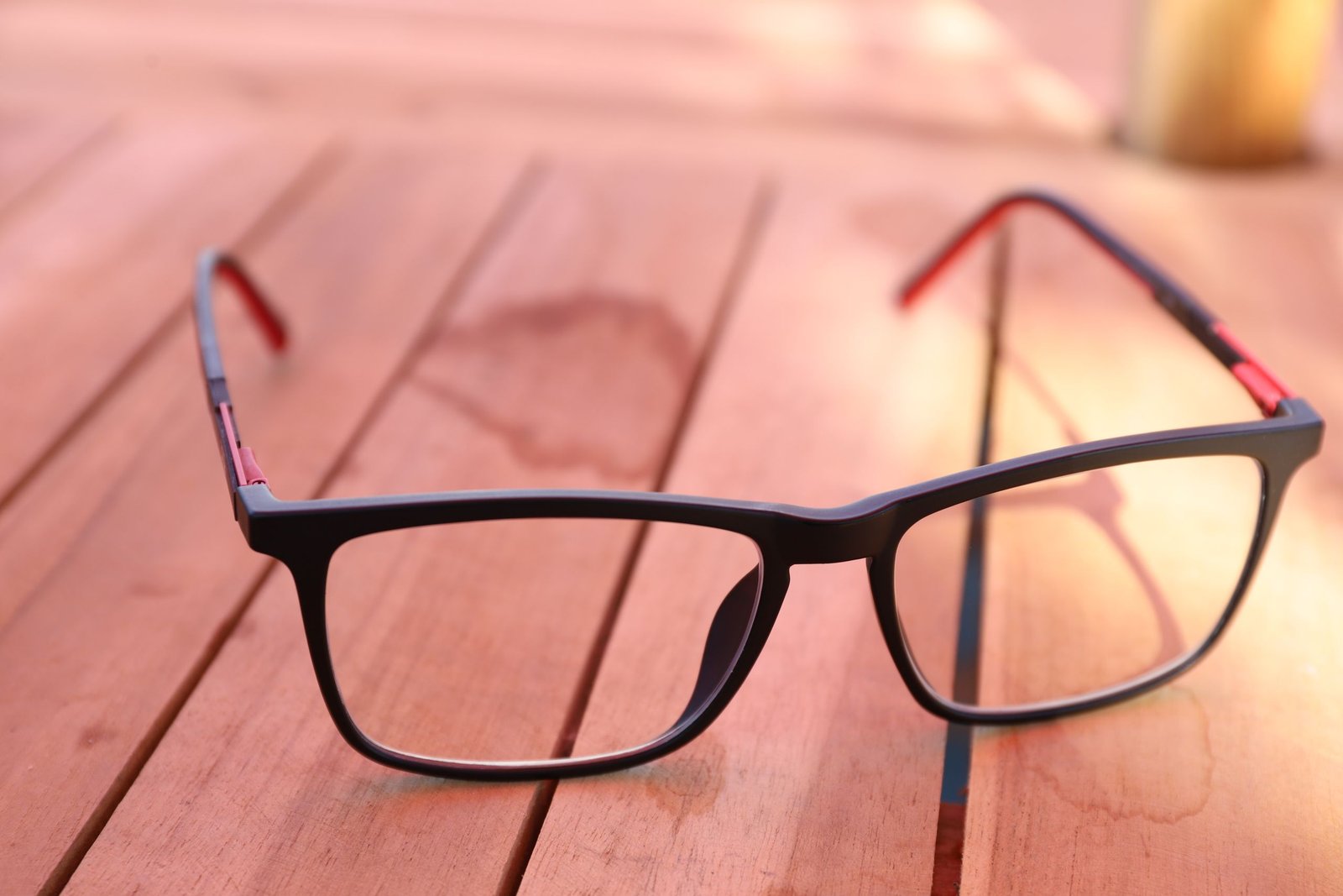 Eyeglasses resting on a wooden table in warm light
