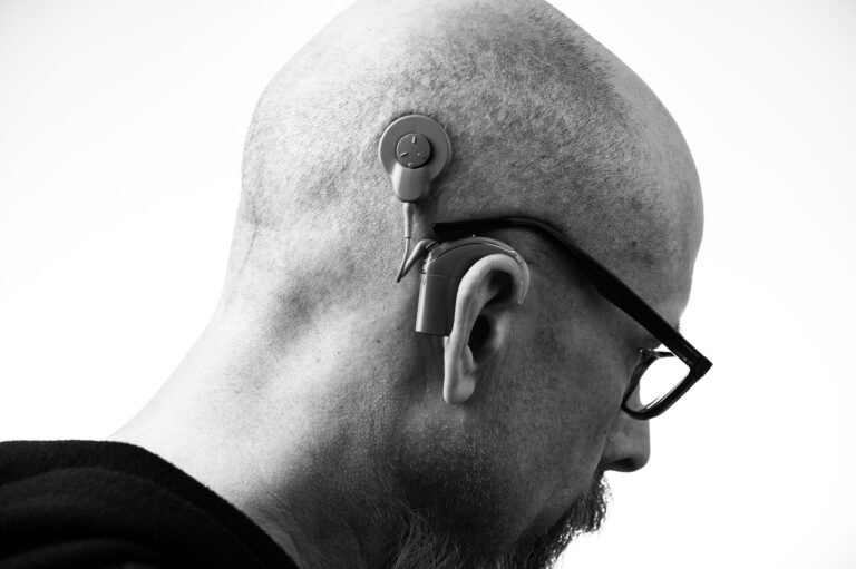 Profile of a person wearing glasses and a hearing aid.