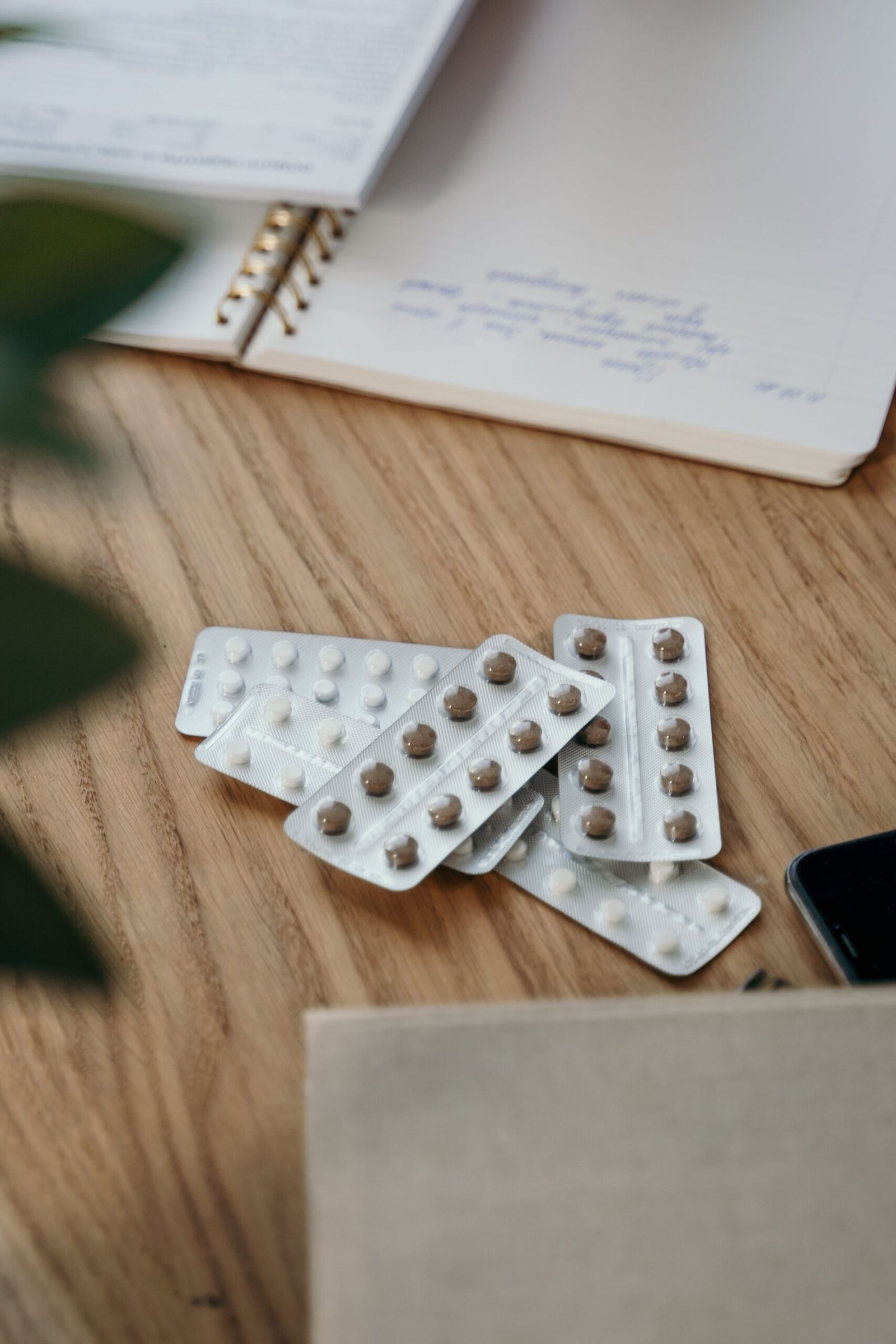 Blister packs of medication beside an open notebook on a table