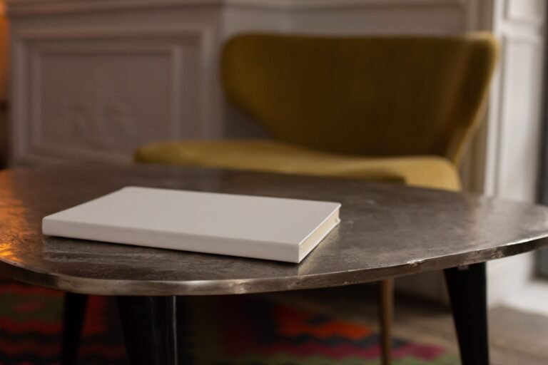 Blank notebook on a small table beside a green armchair in a quiet living room.