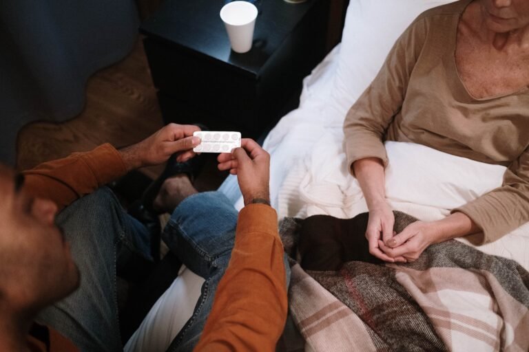 Caregiver discussing medication with an older woman in bed
