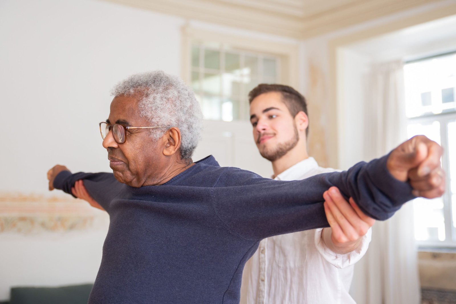Older man doing a guided rehabilitation exercise with a caregiver
