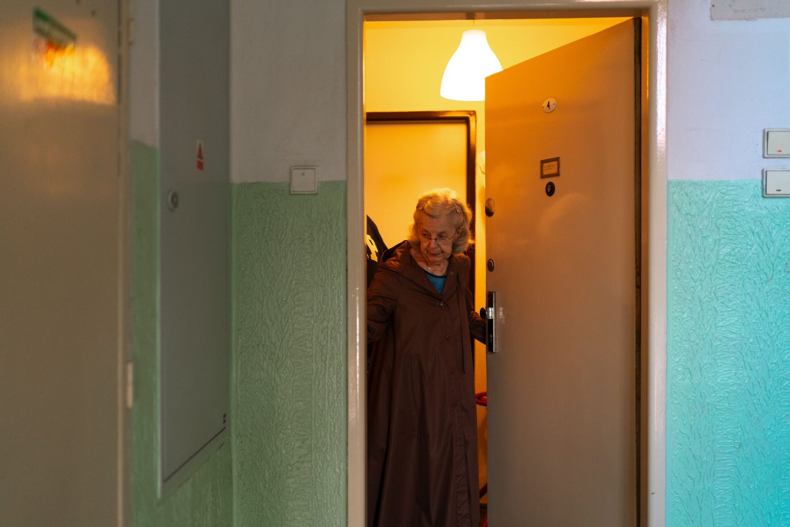 Caregiver assisting an older adult at home near the front door.