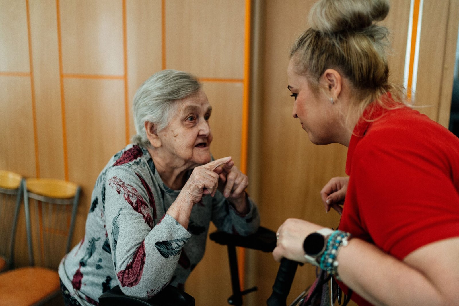 Older woman talking with a caregiver in a residential room