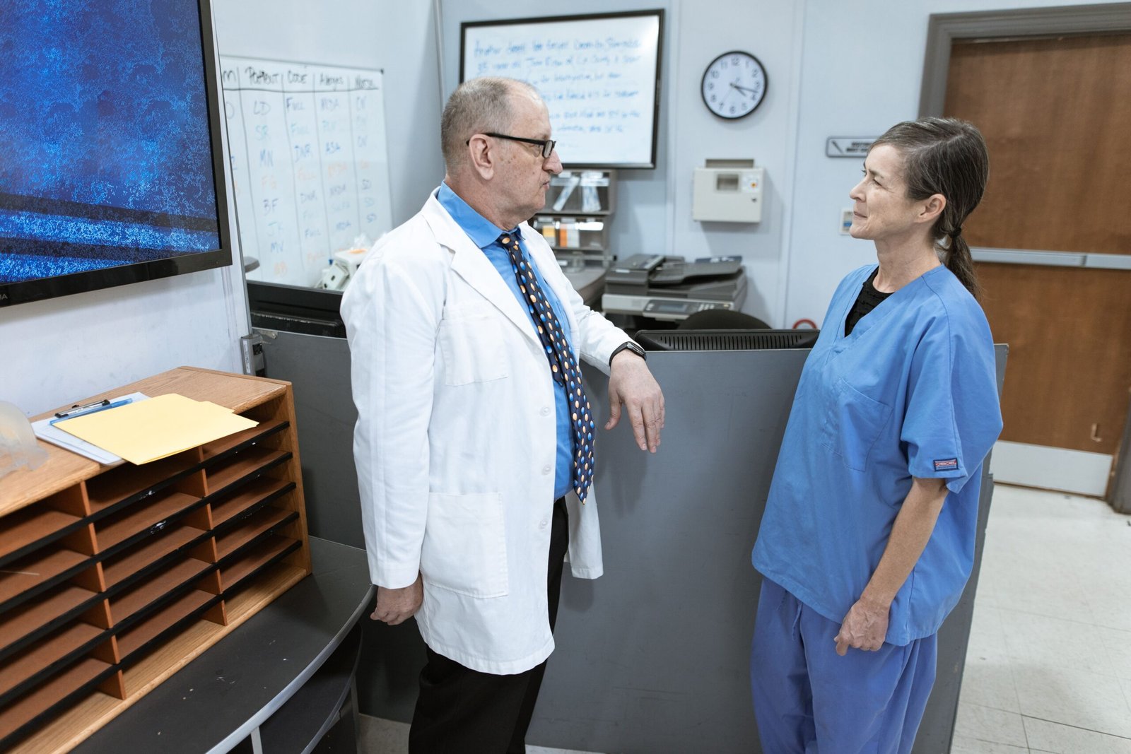 Doctor and nurse discussing care information in a hospital corridor.