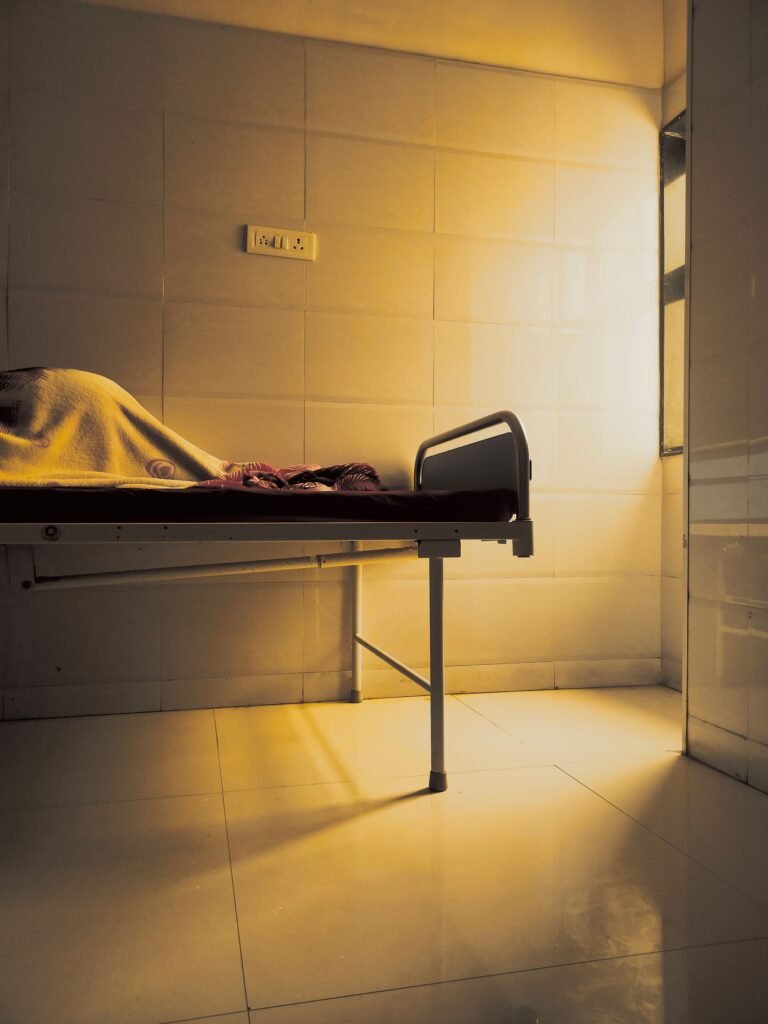 Empty hospital room with a medical bed under warm indoor lighting.