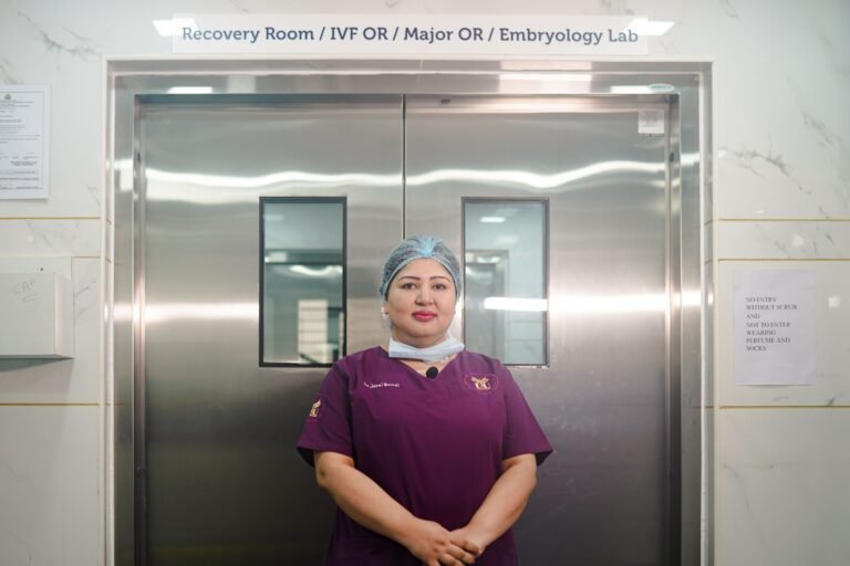 Healthcare professional standing in a bright hospital corridor.