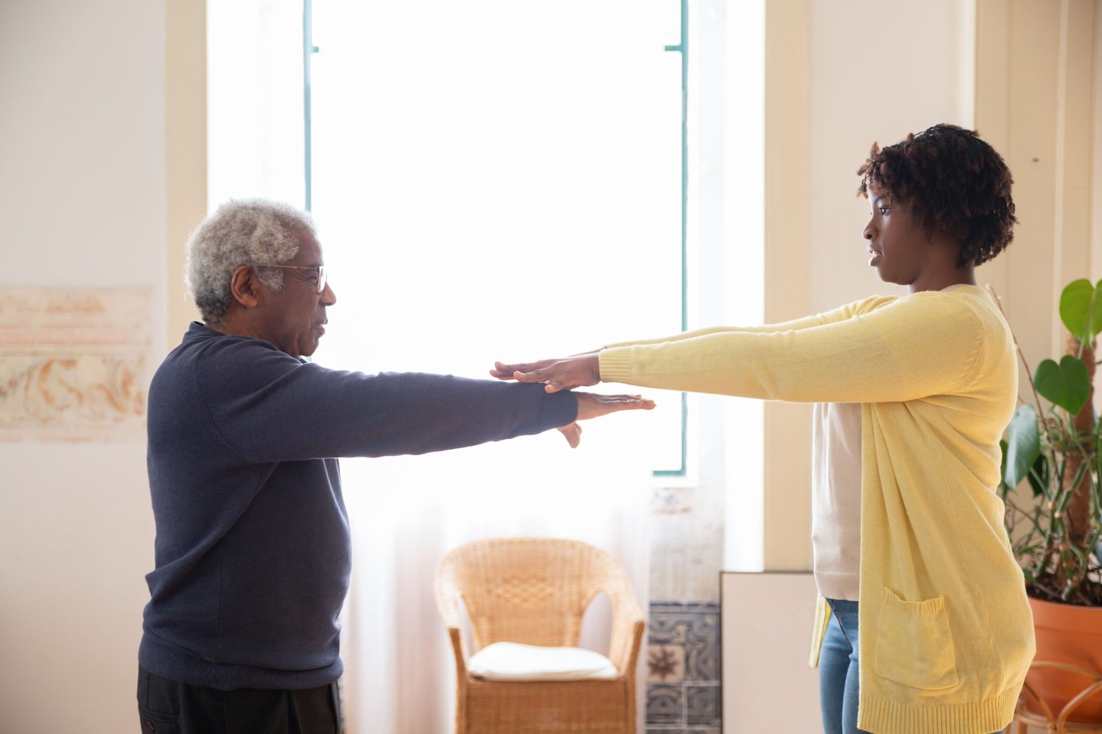 Caregiver guiding an older man during a gentle rehabilitation exercise