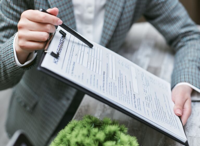 Close-up of a person holding an insurance policy document on a clipboard.