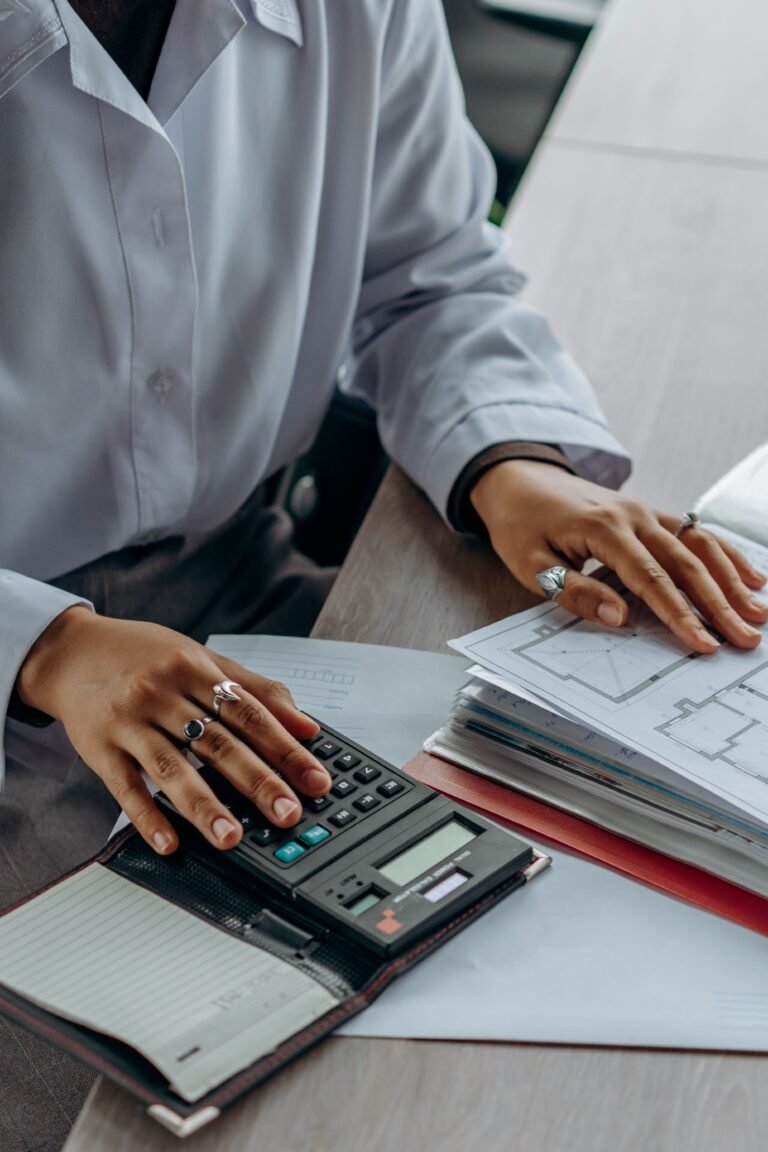 Person using a calculator while reviewing financial documents at a desk.
