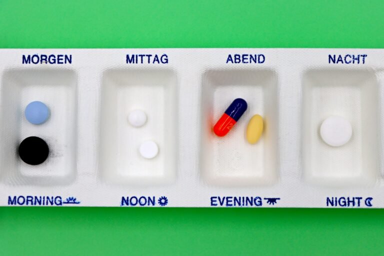 Daily medication organizer with assorted pills on a plain background