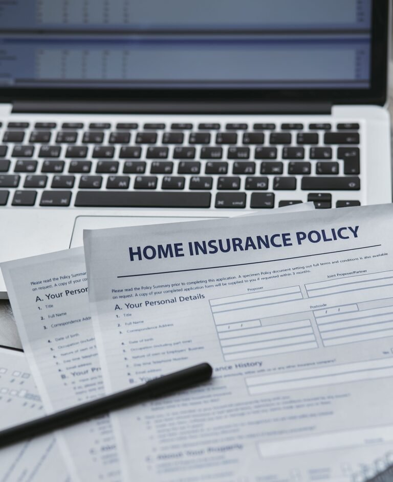 Insurance policy paperwork beside a laptop on a desk.