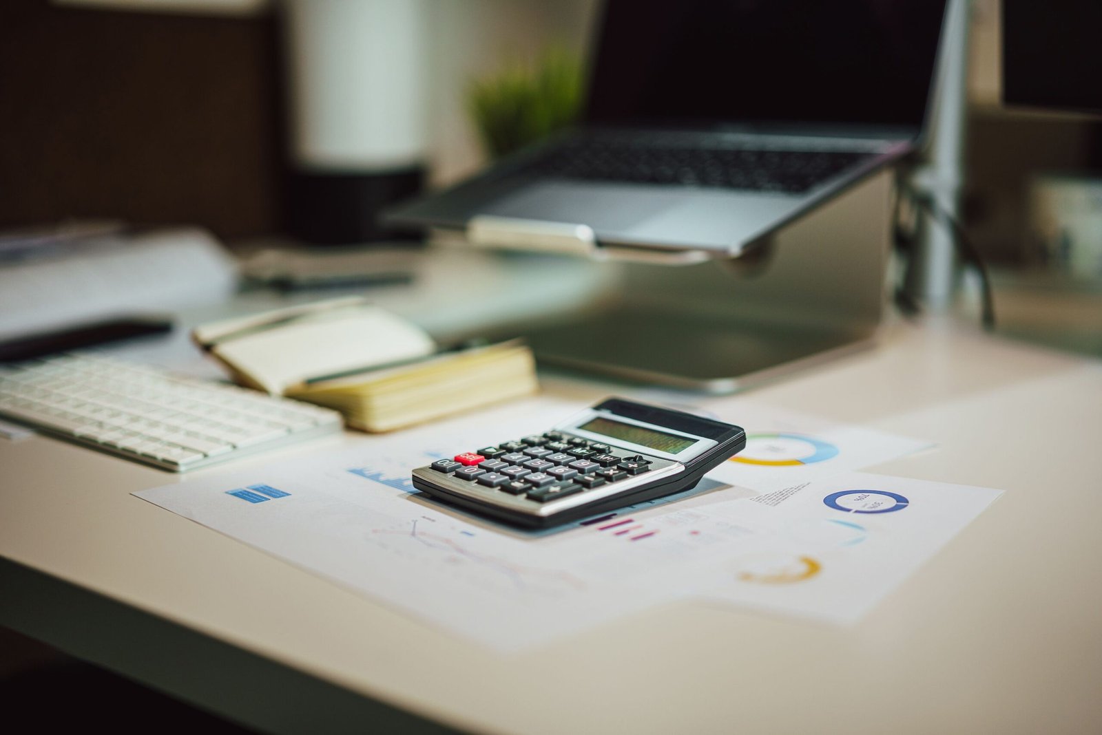 Laptop, calculator, and paperwork arranged for reviewing older bills.