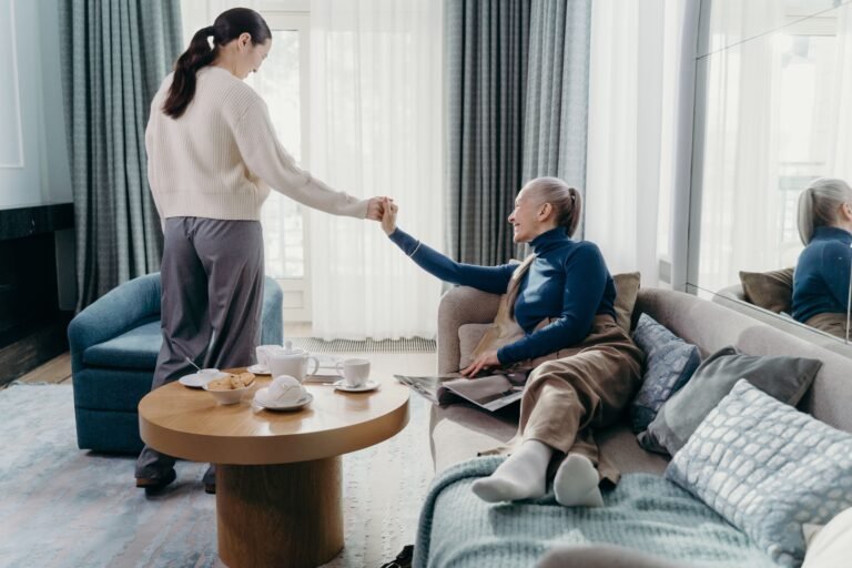 Older woman and adult daughter talking together in a living room.