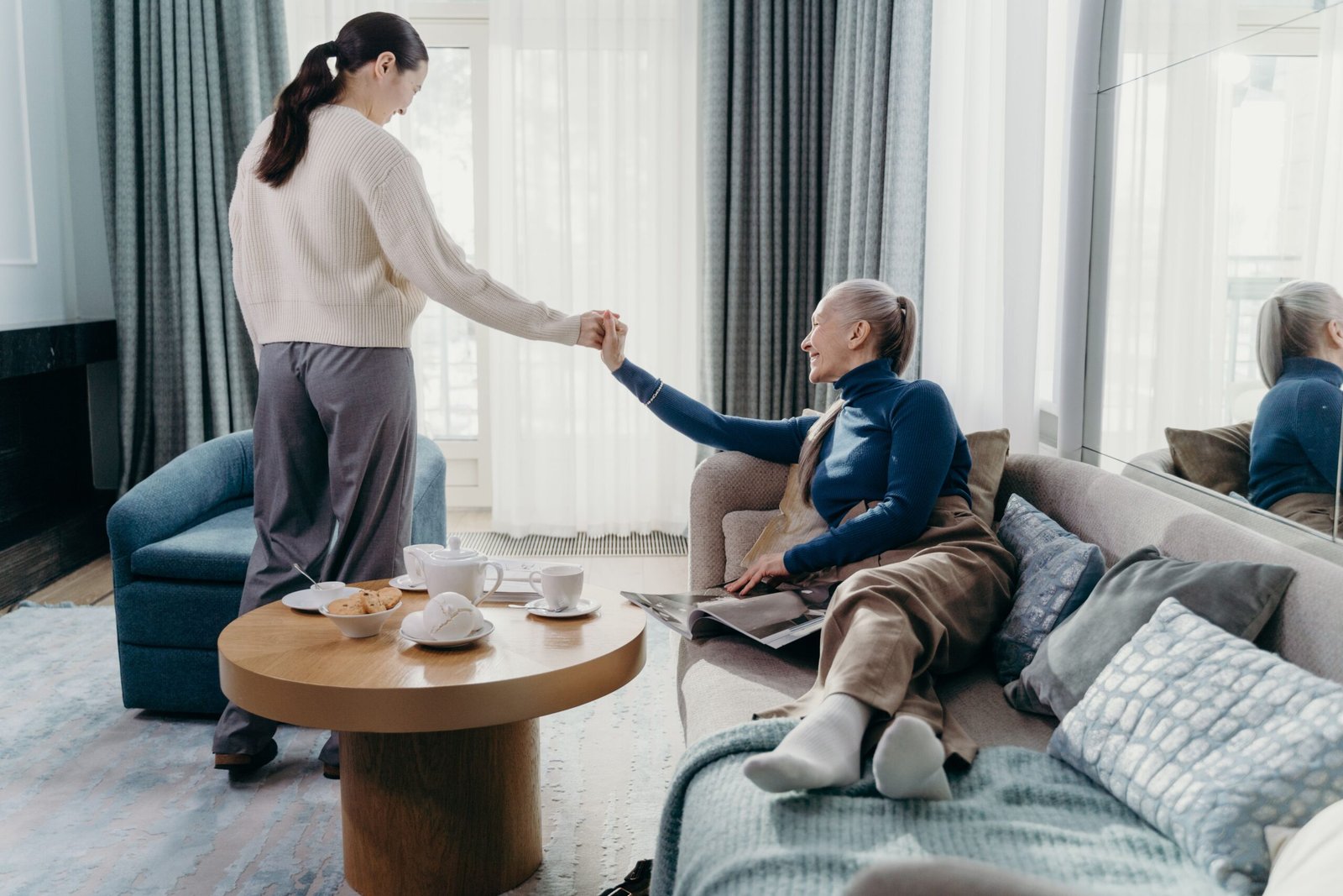 Older woman and adult daughter talking together in a living room.