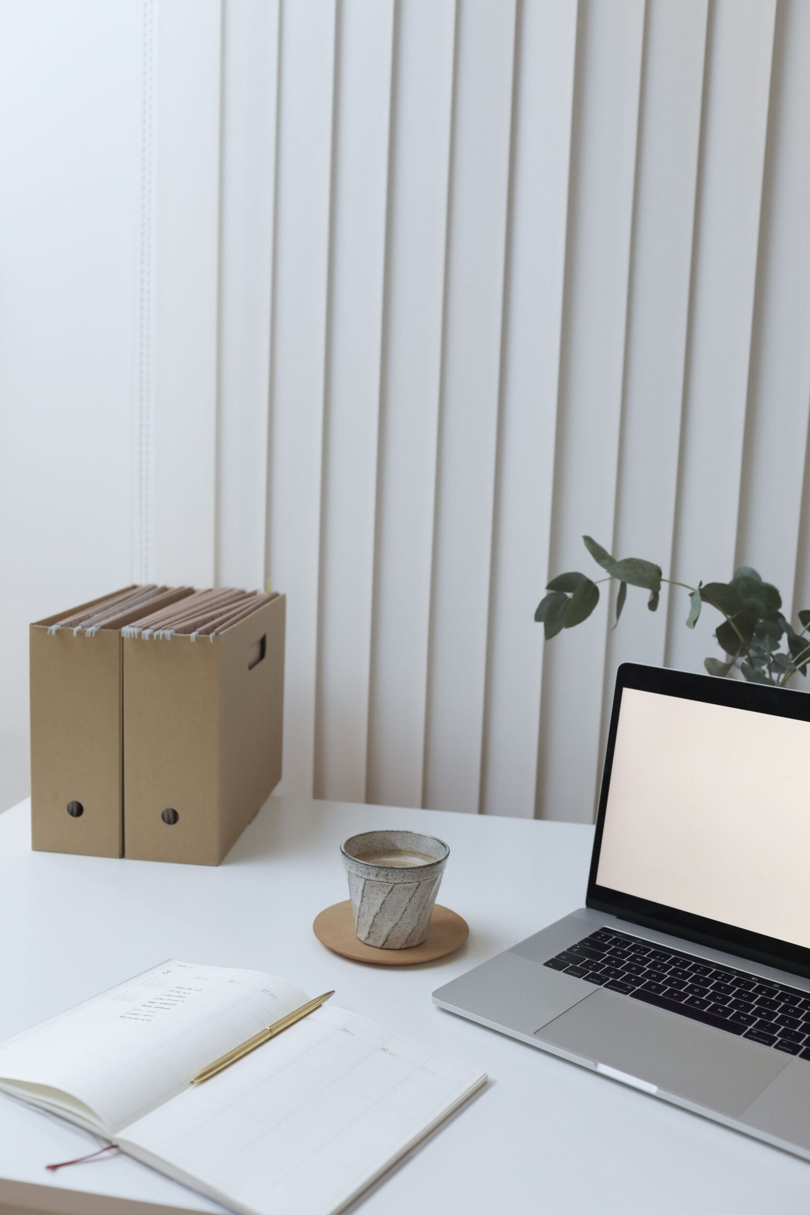 Laptop, notebook, and document folders arranged on a bright office desk