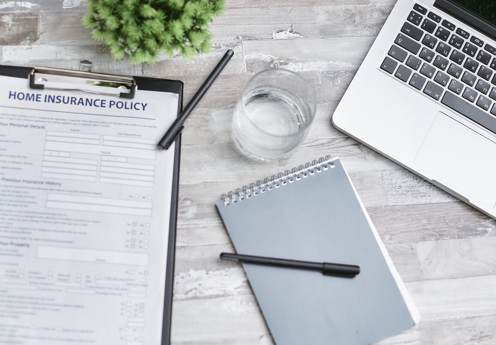 Notebook, laptop, and insurance documents arranged on a desk.