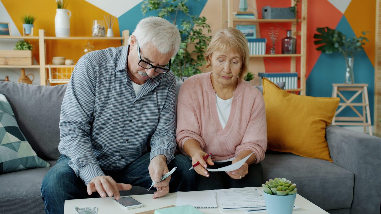 Older couple reviewing paperwork and a smartphone together at home